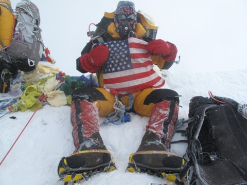 Photo of Bill Burke at the top of Everst holding an American flag.