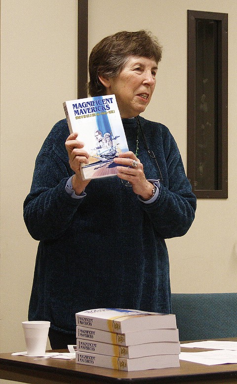 Liz Babcock Holding up a copy of her book and speaking at a book-signing event.