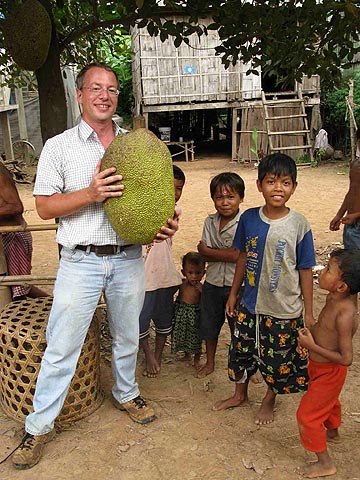 Photo of Daniel Robinson with children from the family that grew the enormous jackfruit he's holding; on Koh Paen, a Mekong island near Kompong Cham, Cambodia