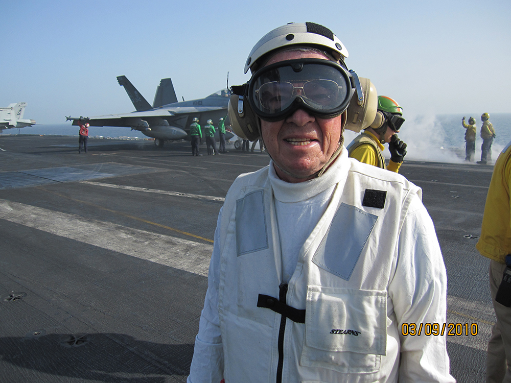 Photo of Nissen Davis and an F/A-18 on the flight deck of the USS Dwight D. Eisenhower on station in the Arabian Gulf